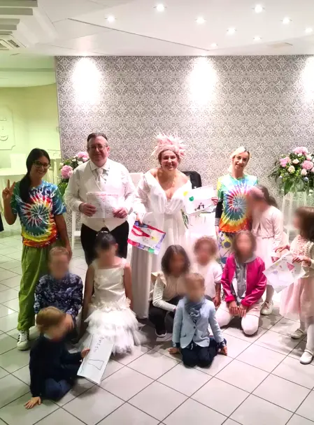 Gli sposi sorridono felici mentre i bambini si divertono con l’animazione durante il matrimonio