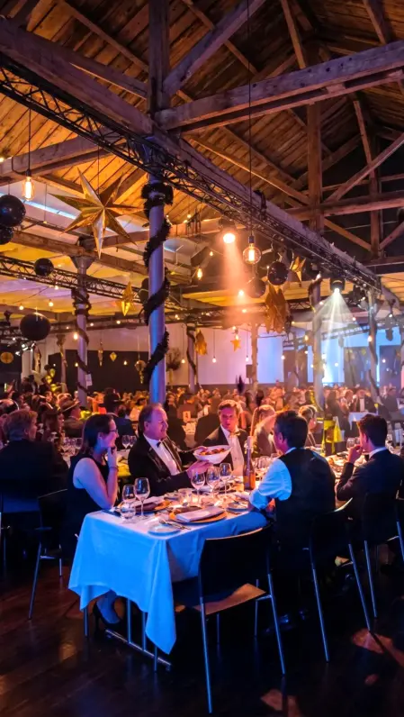 Partecipanti a un evento aziendale durante una cena elegante con tavoli apparecchiati e atmosfera professionale.