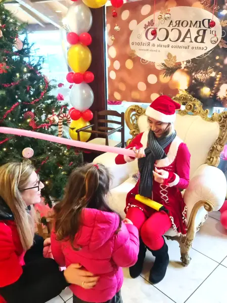 Babbo Natale con animatrici e bambini per feste ed eventi Babbo Natale insieme ad animatrici che intrattengono bambini in un centro commerciale