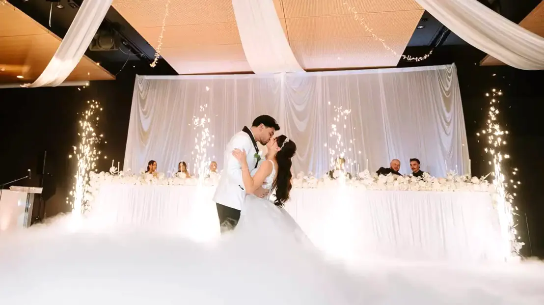 Momento spettacolare del ballo degli sposi con effetto fumo basso e fontane fredde scintillanti, creando un'atmosfera da sogno durante il matrimonio