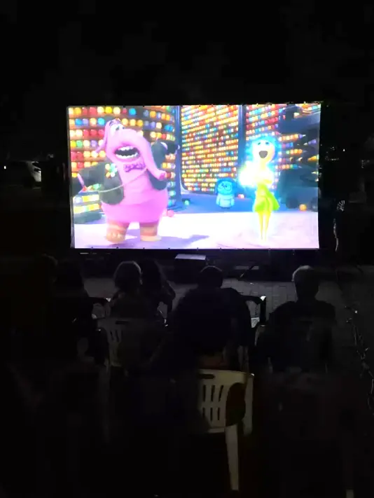 Cinema all’aperto con maxi schermo Spettatori guardano un film in un'area all’aperto con videoproiettore