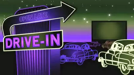 Drive-in con proiezione su maxi schermo Auto parcheggiate davanti a un grande schermo per un’esperienza drive-in