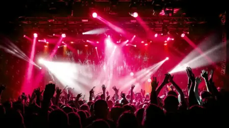 Un grande evento con palco, luci e pubblico in una piazza o spazio al chiuso